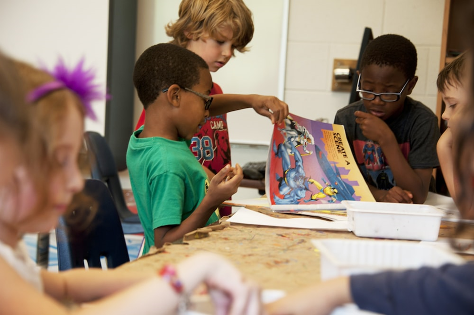 Children around table looking at book